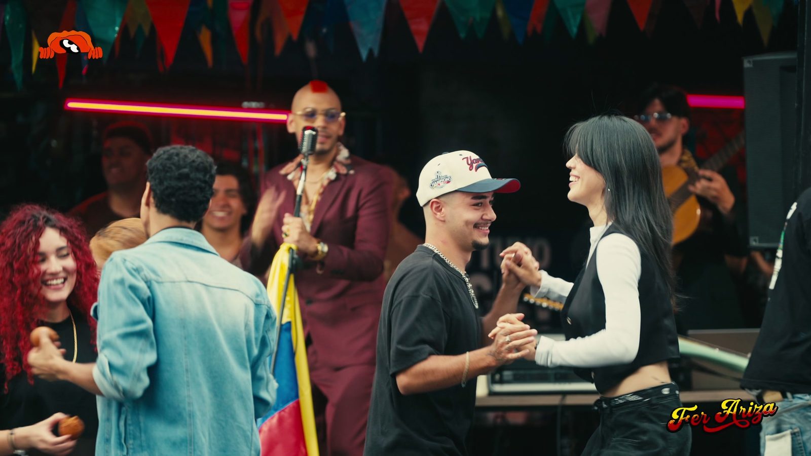 Fer Ariza cantando en la parranda del Tributo Parrandero, con gente bailando y la bandera de Colombia